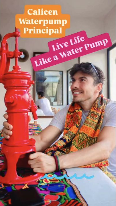 Adrian smiling at and holding the antique red water pump he brought home